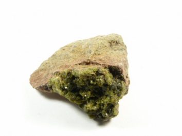 Epidot - kamień naturalny, surowy, nieszlifowany. Kawałek skały z zielonym minerałem o krystalicznej strukturze na białym tle.