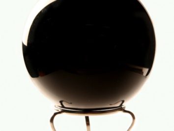 Czarna kula do wróżenia ustawiona na metalowym stojaku, widok z przodu.
