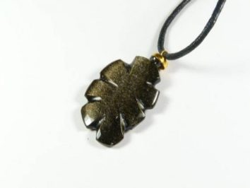 Czarny wisiorek w kształcie liścia na czarnym sznurku, na białym tle.