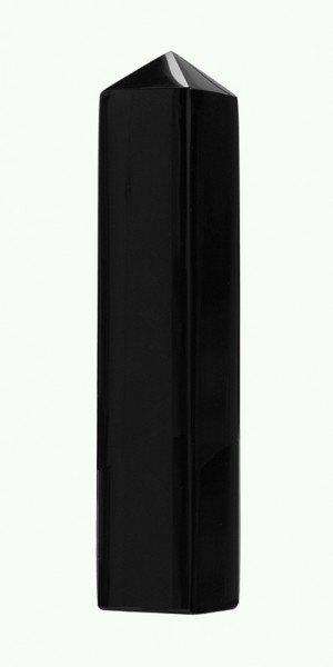 Czarny kryształowy obelisk o sześciokątnym przekroju na jasnym tle.