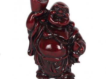 Ciemnoczerwona figurka uśmiechniętego Buddy z uniesionym w górę złotym sztabkiem.