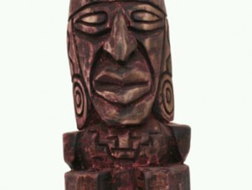 Drewniana rzeźba przedstawiająca stylizowaną postać z szeroką twarzą i geometrycznymi wzorami.