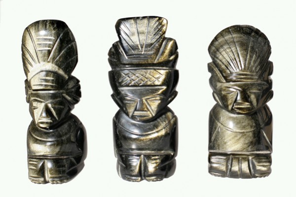 Trzy kamienne figurki przedstawiające postacie z indiańskimi pióropuszami ustawione obok siebie.