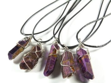 Pięć fioletowych kryształów na czarnych sznurkach, oplecionych drutem jako naszyjniki.