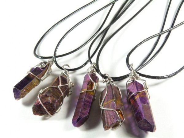 Pięć fioletowych kryształów na czarnych sznurkach, oplecionych drutem jako naszyjniki.