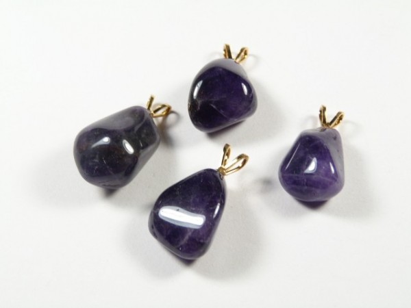 Cztery fioletowe kamienie półszlachetne z zawieszkami, leżące na białym tle.
