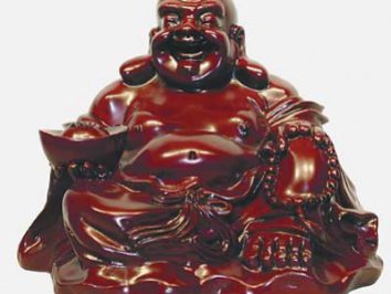 Czerwona figurka siedzącego Buddy z miseczką i koralikami w ręku.