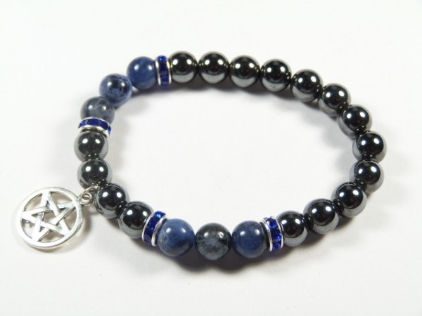 Bransoletka z ciemnych koralików z zawieszką pentagramu na białym tle.