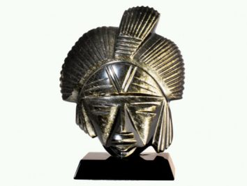 Rzeźba afrykańskiej głowy z ciemnego kamienia na czarnej podstawie.