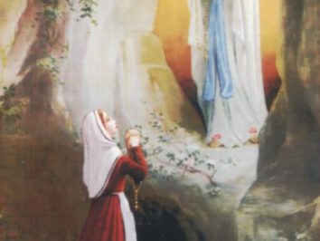 Kobieta modli się przed Matką Boską w grocie w Lourdes.