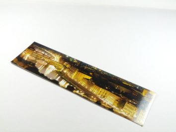 Zakładka do książki z panoramą miasta nocą, leżąca na białym tle.