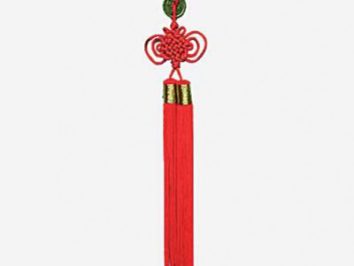 Czerwony chiński węzeł ozdobny z długimi frędzlami, wiszący na białym tle.