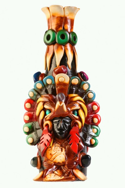 Kolorowa figurka przedstawiająca postać w pióropuszu inspirowanym kulturą aztecką.