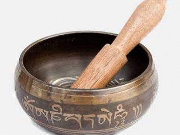 Miseczka tybetańska z drewnianym pałeczką, używana do medytacji i relaksacji.
