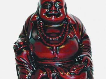 Czerwona figurka uśmiechniętego Buddy siedzącego z koralami na szyi.