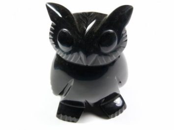 Czarna figurka sowy wykonana z kamienia, widok z przodu na białym tle.