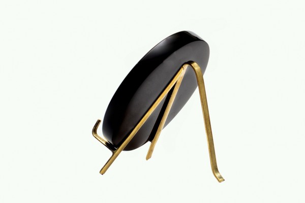 Czarny zegar stołowy na złotej, metalowej podpórce na białym tle.