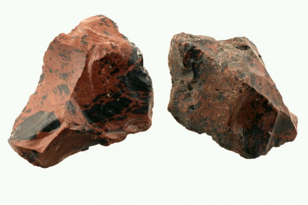 Dwa kawałki czerwono-czarnego krzemienia leżące na jasnym tle.