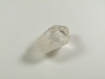 Przezroczysty kryształ kwarcu leżący na białym tle.