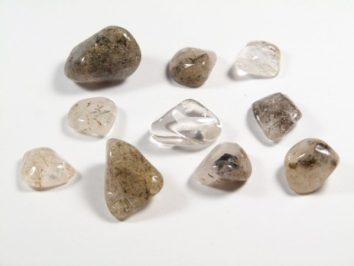 Aktynolit - kamień gładzony, polerowany, szlifowany i bębnowany w formie otoczaka. Dziesięć wypolerowanych kamieni aktynolitu na białym tle.