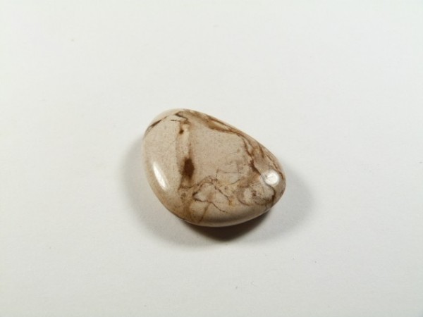 Agat szlifowany płaski. Polerowany kamień agat leży na białym tle.