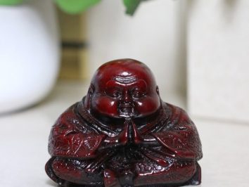 Figurka Buddy w pozycji siedzącej z dłońmi złożonymi do modlitwy.