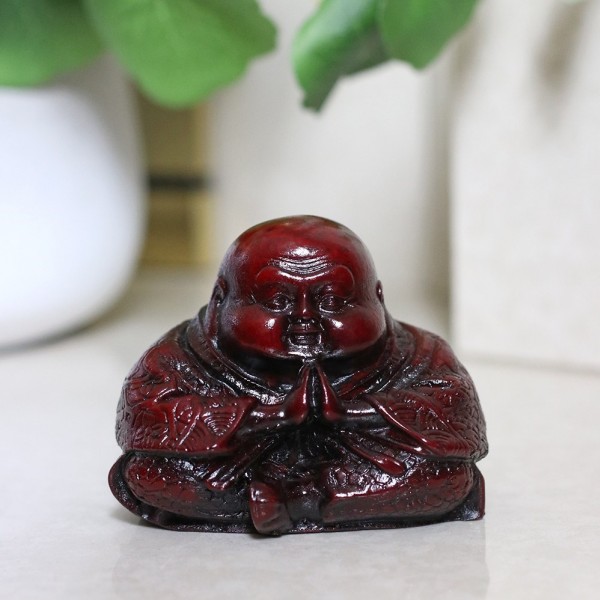Figurka Buddy w pozycji siedzącej z dłońmi złożonymi do modlitwy.