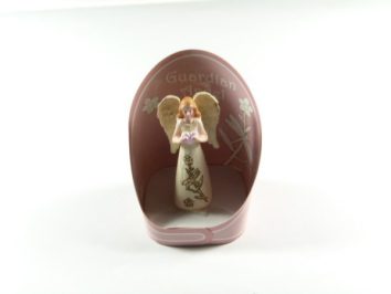 Figurka anioła stróża w białej szacie, ustawiona w różowym owalnym pudełku.