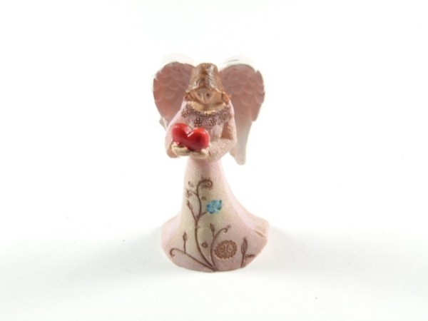 Figurka anioła w różowej sukni trzymającego czerwone serce w dłoniach.