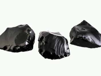 Trzy czarne bryły obsydianu na jasnym tle.