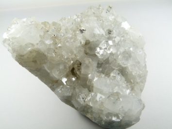 Biała bryła kryształów kalcytu na jasnym tle.