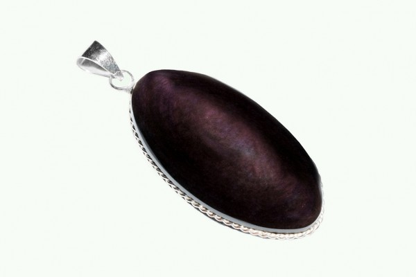 Ciemnofioletowy kamień w srebrnej oprawie, tworzący wisior na jasnym tle.