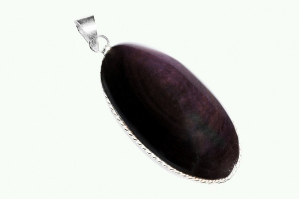 Srebrny wisiorek z ciemnym, owalnym kamieniem ozdobnym na jasnym tle.