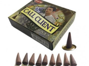 Pudełko stożków zapachowych Call Client oraz dziesięć stożków ułożonych przed opakowaniem.