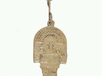 Breloczek z metalową zawieszką w kształcie postaci ozdobionej wzorami, na białym tle.