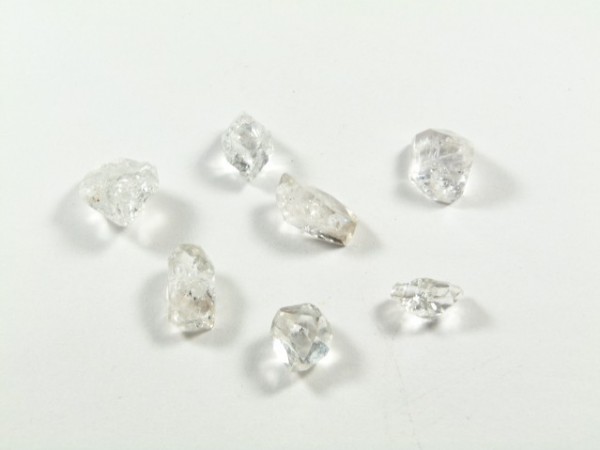 Diament Herkimer - kamień naturalny surowy nieszlifowany. Siedem surowych diamentów leży na białym tle.