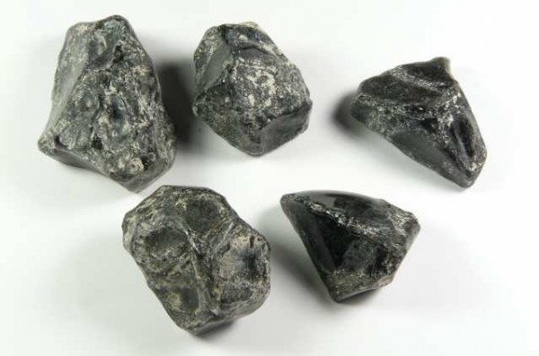 Pięć surowych czarnych kamieni leży na białym tle.