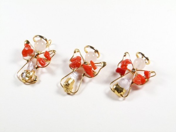 Trzy ozdoby w kształcie aniołków z drutu i czerwonych kamieni na białym tle.