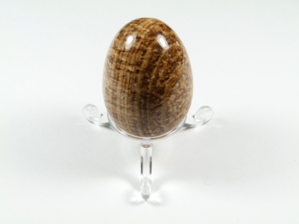 Jajko aragonit brązowy szlifowany. Jajko z brązowego kamienia polerowanego na przezroczystej podstawce, na białym tle.