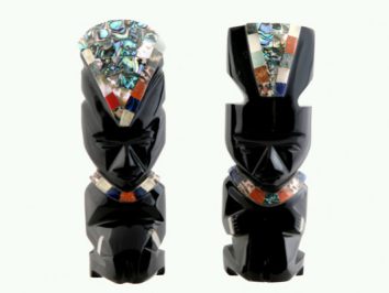 Dwie czarne figurki z kamienia ozdobione kolorowymi wstawkami, ustawione obok siebie.