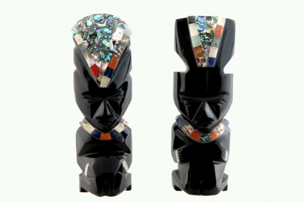 Dwie czarne figurki z kamienia ozdobione kolorowymi wstawkami, ustawione obok siebie.