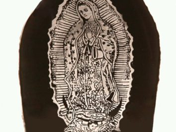 Czarna figura z wizerunkiem Matki Boskiej z Guadalupe z aureolą i złożonymi dłońmi.