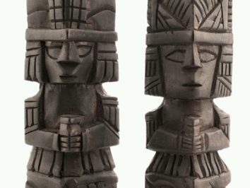 Dwie drewniane figurki o stylu azteckim, ustawione obok siebie, trzymające przedmioty w dłoniach.