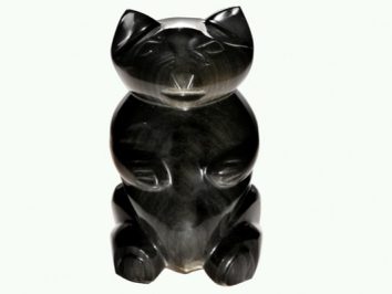 Czarna figurka niedźwiedzia wykonana z kamienia, ustawiona na białym tle.