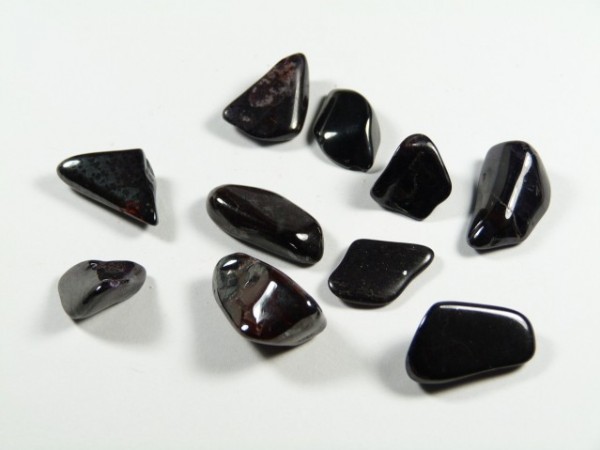Dziesięć gładkich, czarnych kamieni leży na białym tle.
