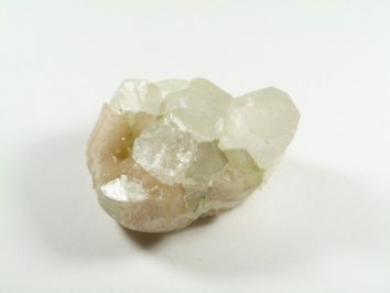 Białawy kryształ minerału na białym tle.