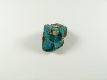 Chryzokola kamień naturalny nieszlifowany surowy. Niebieski kamień minerału turkusu leży na białym tle.