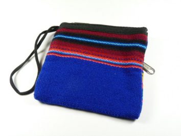 Mała, kolorowa torebka z tkaniny z niebieskim i czerwonym wzorem, leży na białym tle.