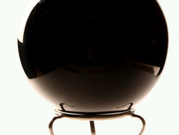 Czarna kula na metalowym stojaku, ustawiona na jasnym tle.
