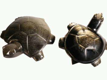 Dwa figurki żółwi z czarnego kamienia ustawione na jasnym tle.